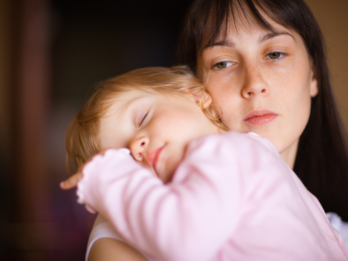 Foto: Traurige Frau mit Kleinkind auf dem Arm